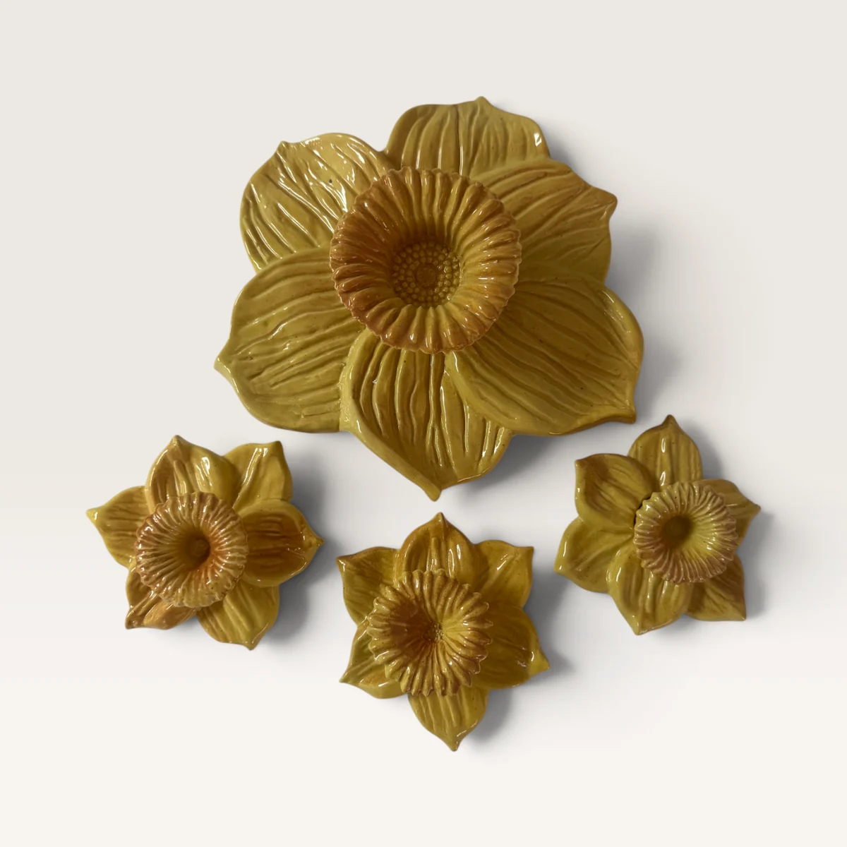 Five ochre-yellow ceramic daffodils: one large bloom and four small ones