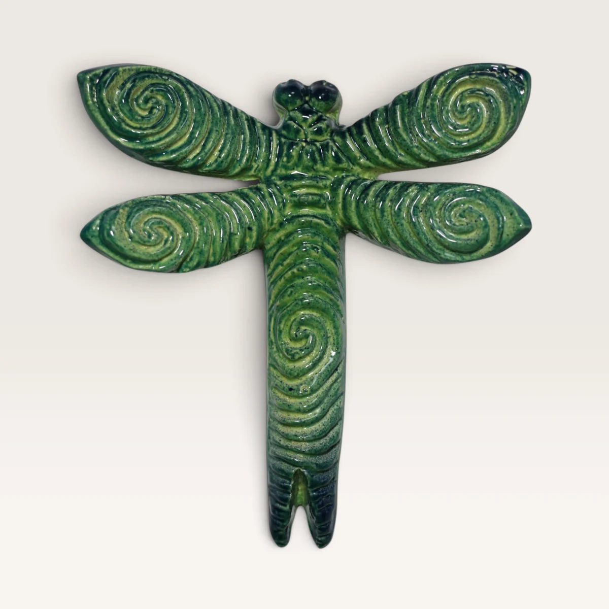 Green ceramic dragonfly with spirals carved into its wings and body