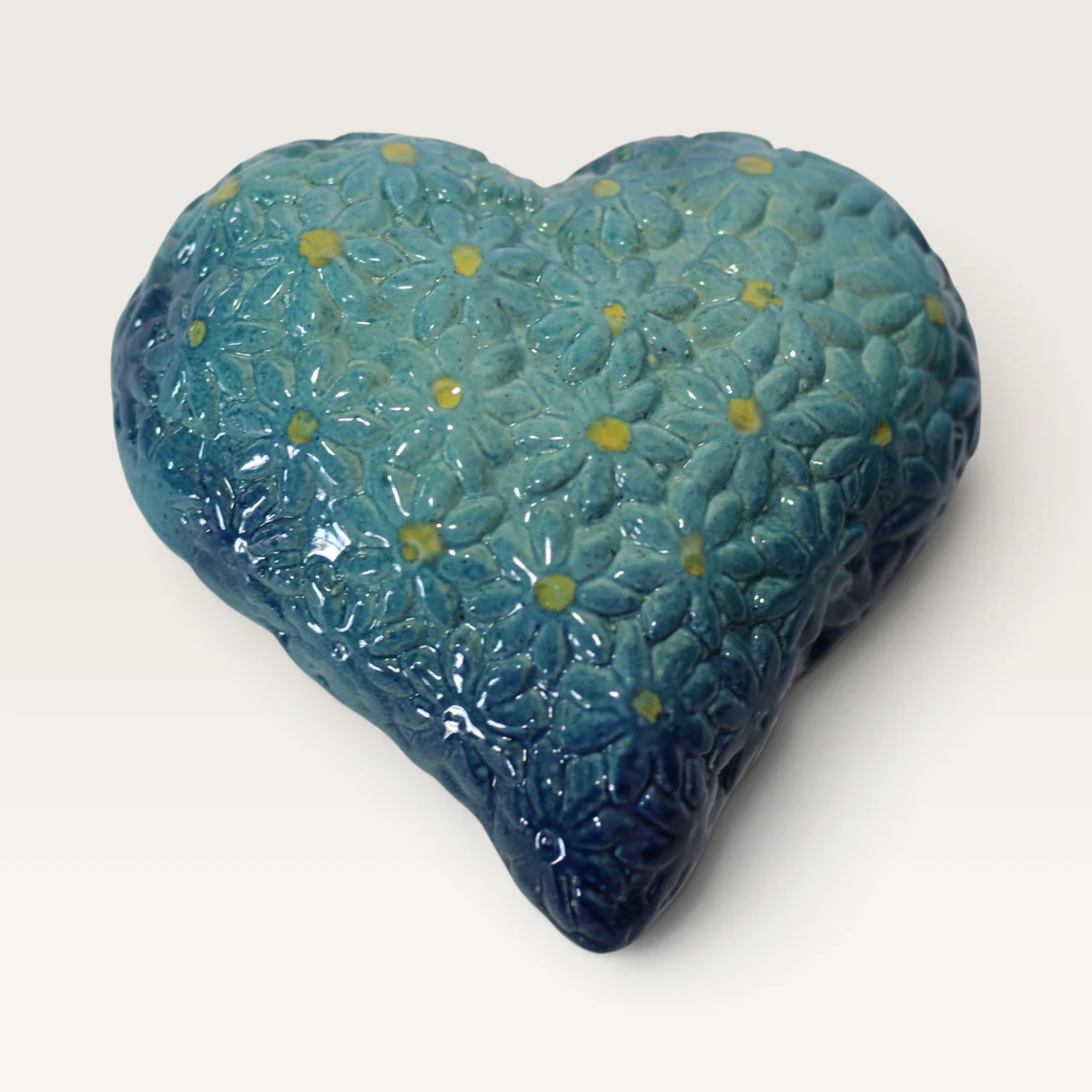 Puffy ceramic heart covered in raised daisies, turquoise shading to deep blue at the edges