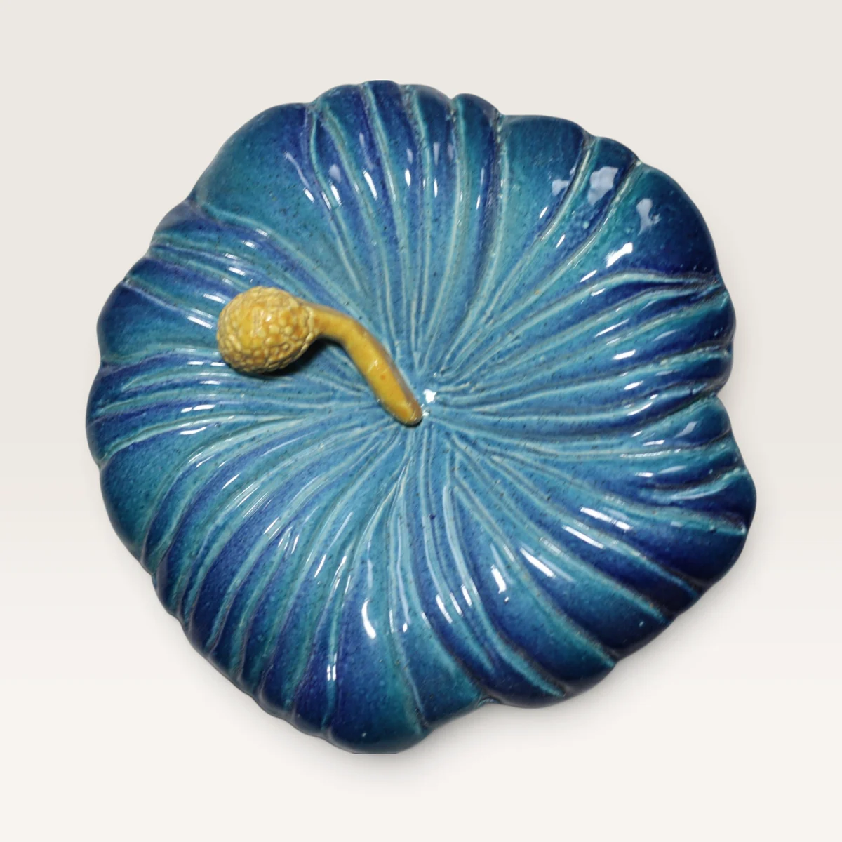 Blue ceramic hibiscus flower with ribbed petals and a yellow stamen