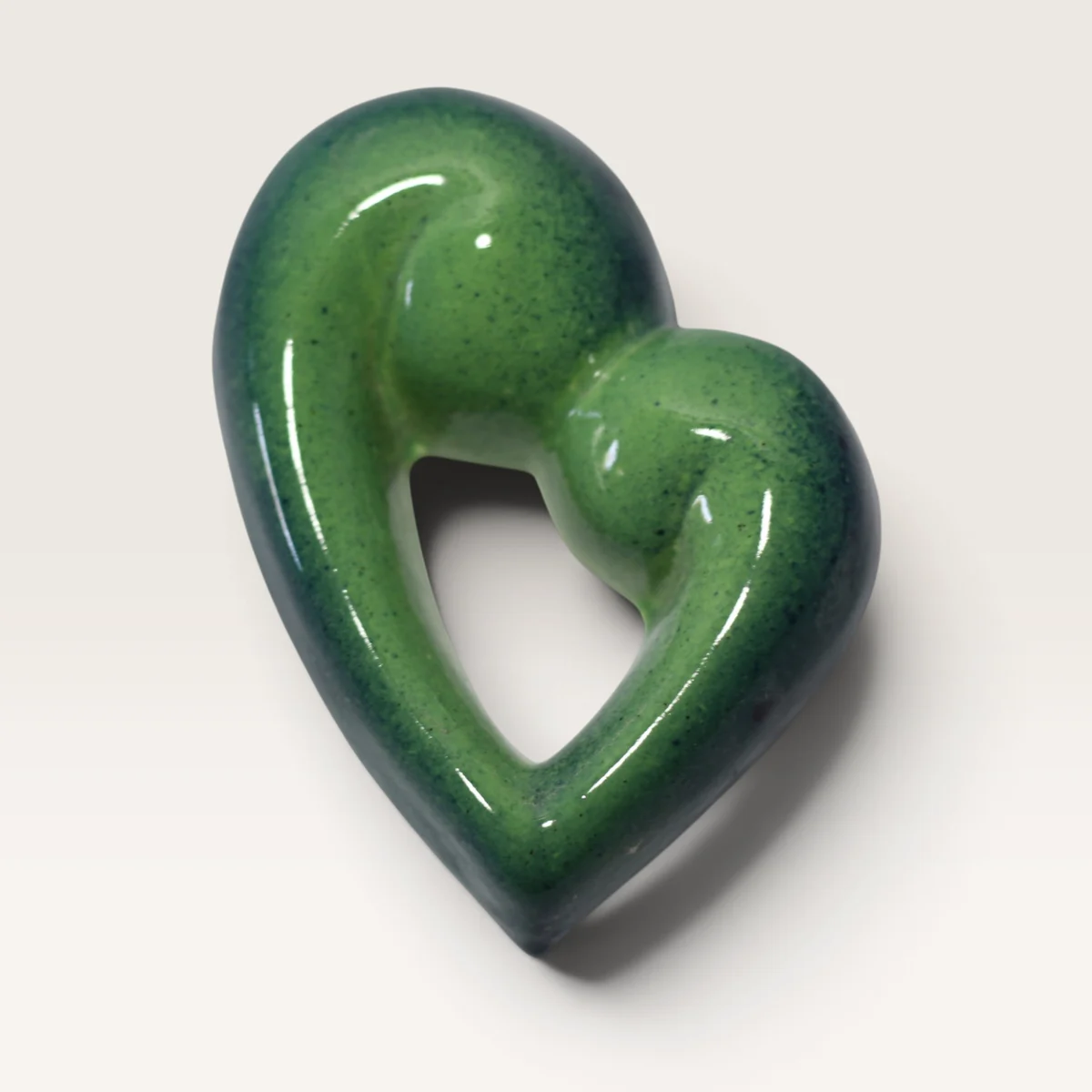 Open heart in a speckled green glaze, formed by two curling koru