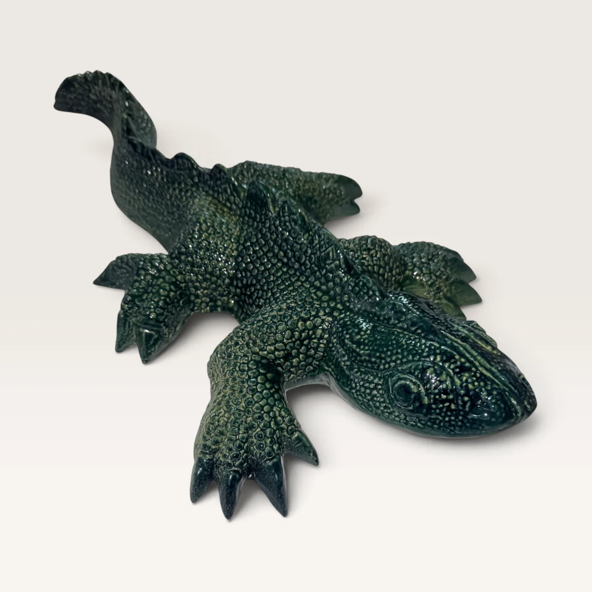 Large dark green ceramic gecko, finely scaled, with its head raised and claws spread
