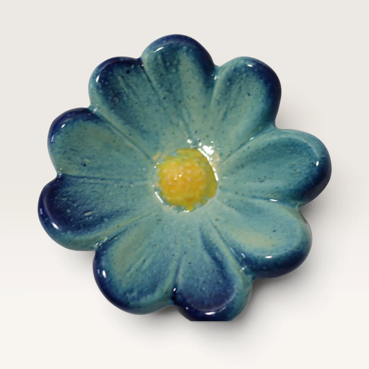 Round-petalled ceramic flower in pale blue shading to deep blue, with a yellow centre