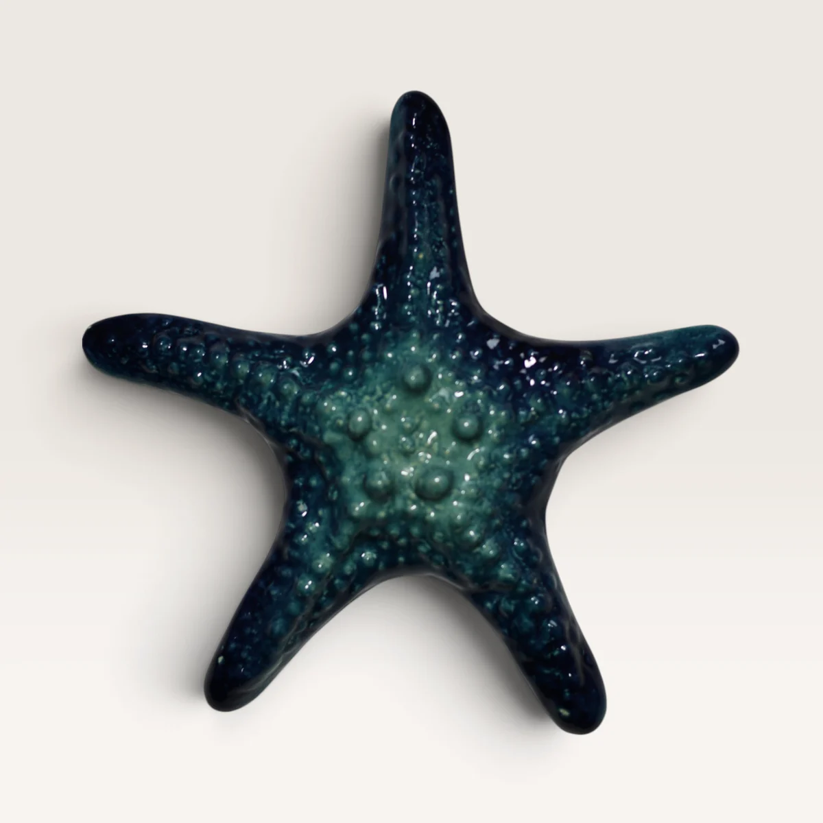 Deep blue-green ceramic starfish with a bumpy texture, lighter at the centre