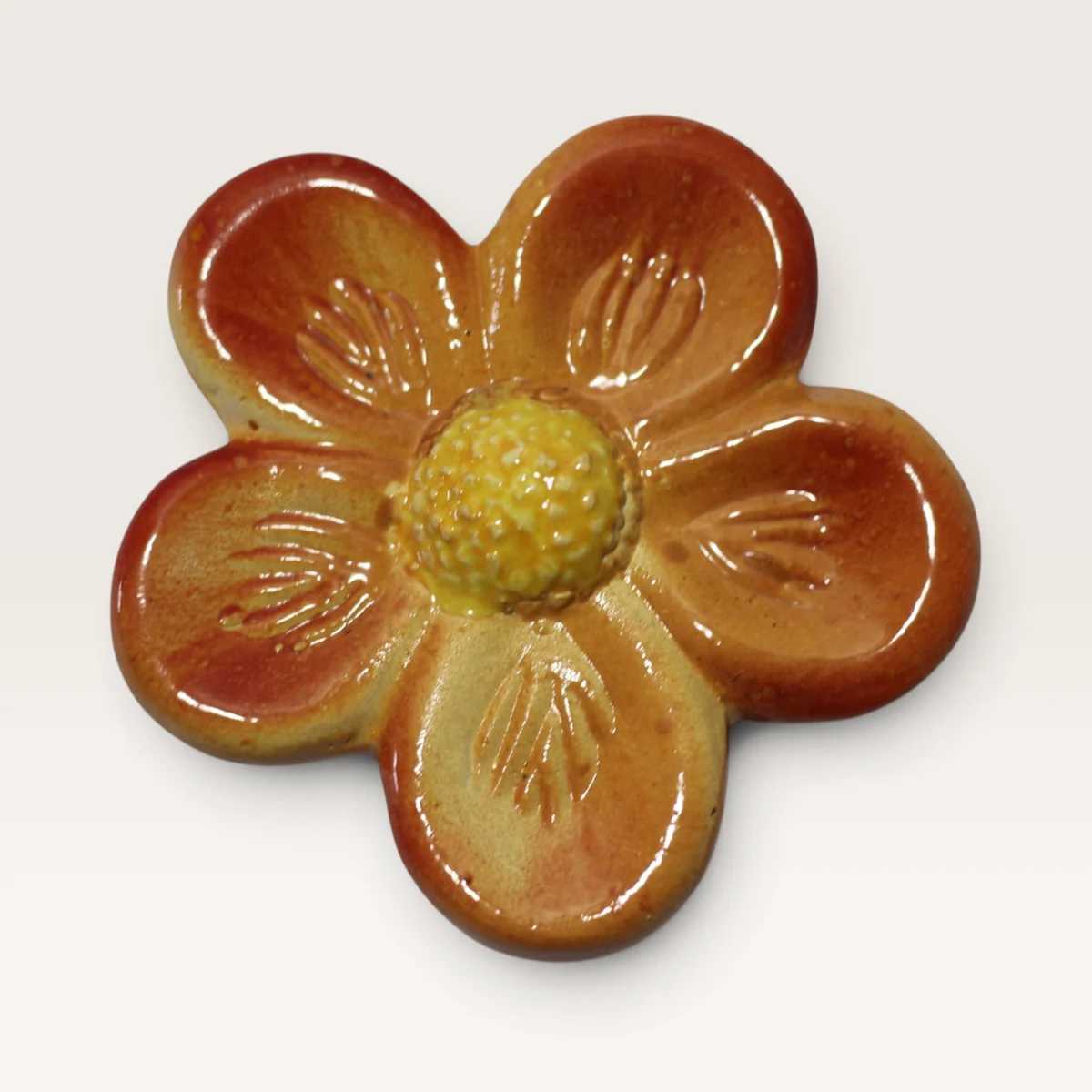 Small five-petal ceramic flower in orange with a textured yellow centre