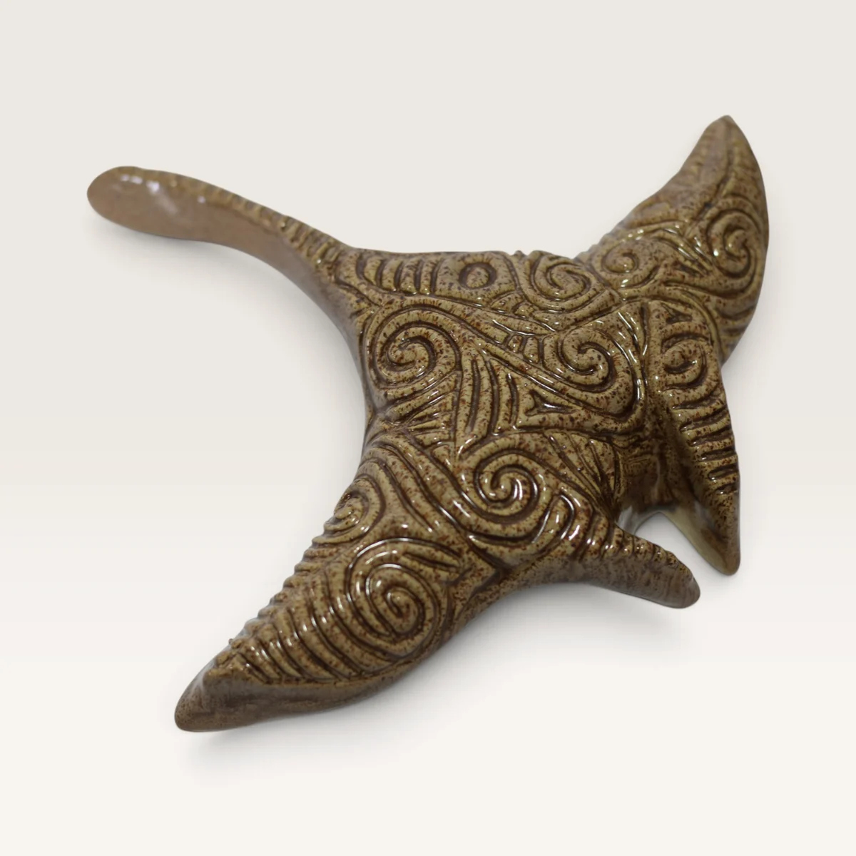 Brown ceramic manta ray carved all over with koru swirls