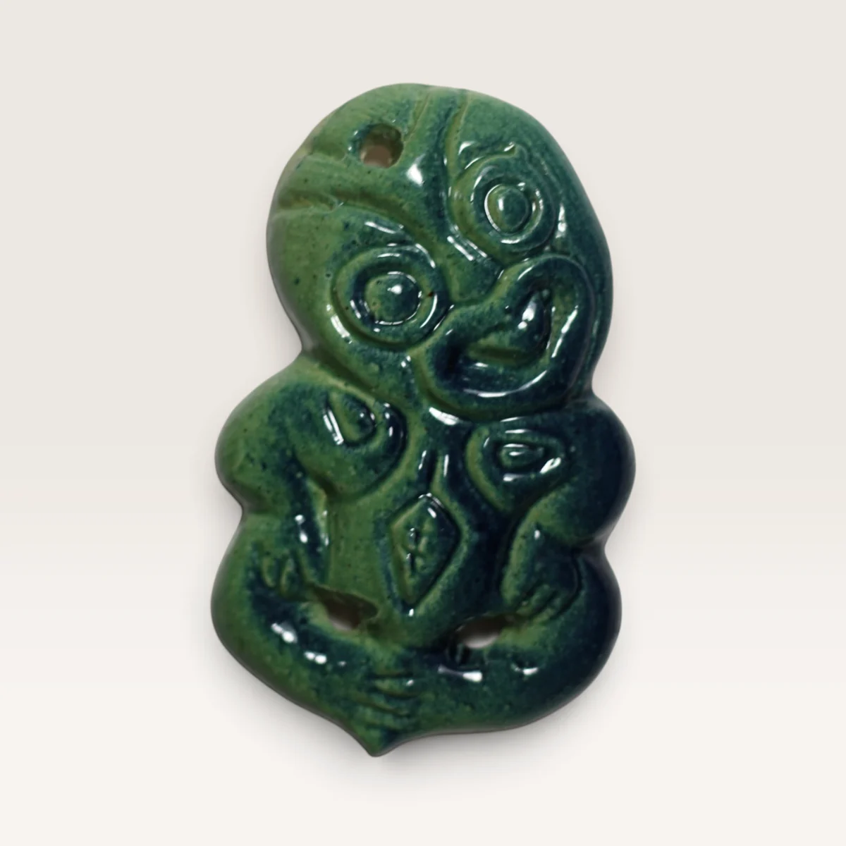 Small green ceramic hei tiki with carved spiral details