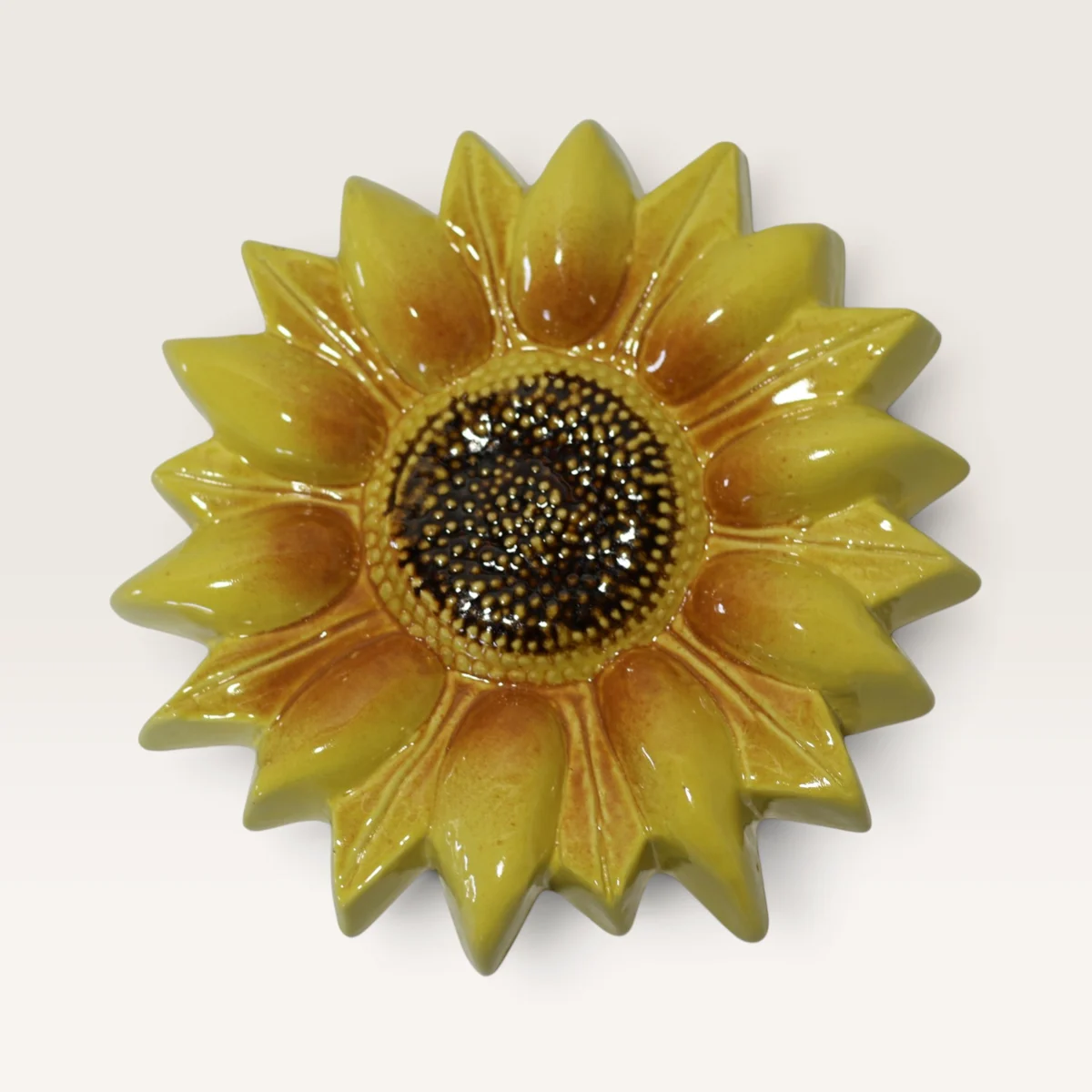 Yellow ceramic sunflower with layered pointed petals and a dark seeded centre