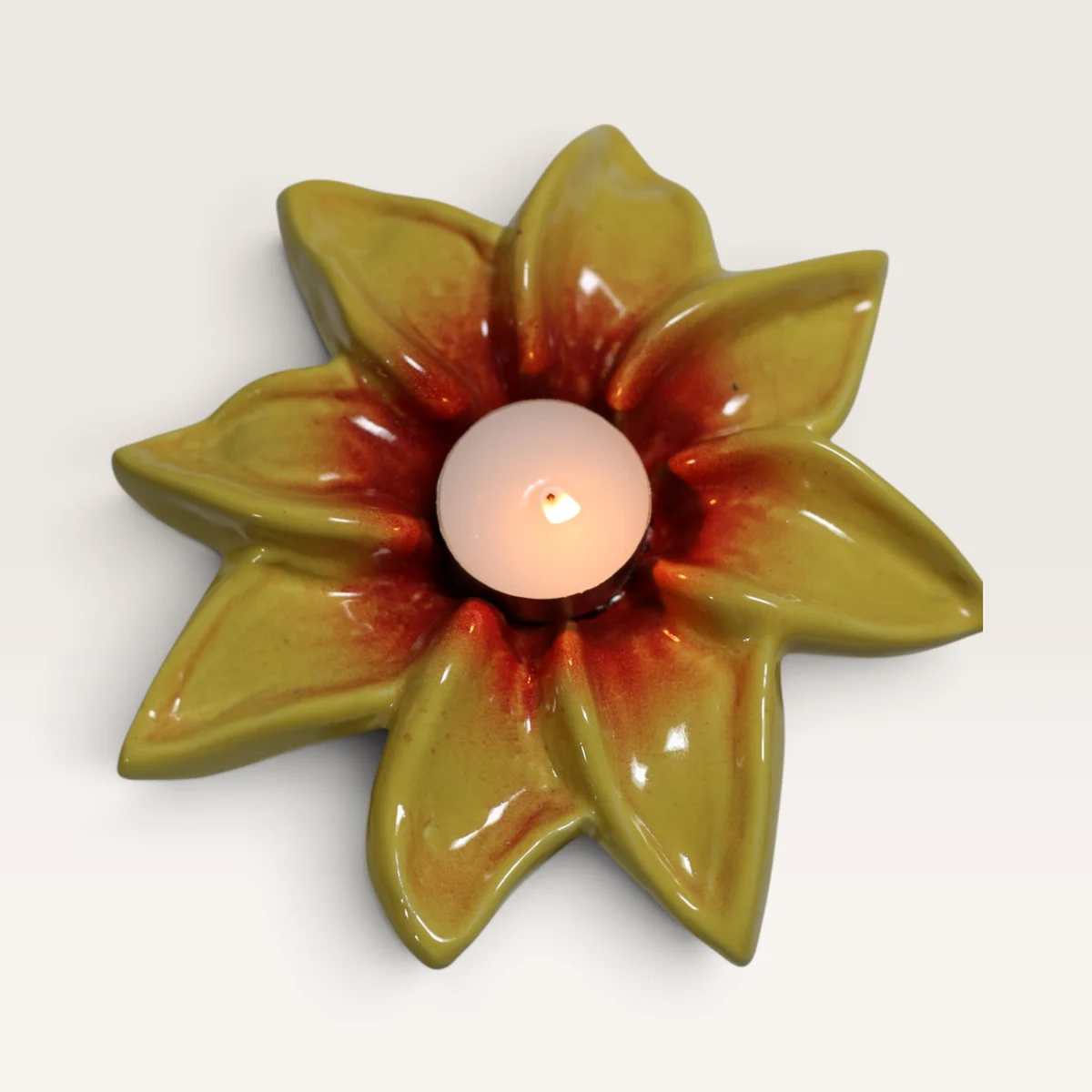 Yellow ceramic flower tealight holder, red at the centre, with a lit tealight in it